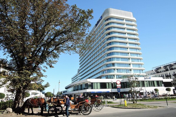 A modern hotel with a curved facade, large windows, and a prominent sign.