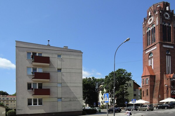 A modern building with balconies and a red brick tower with a clock. - Apartment in Swinoujscie Near Baltic Beach (Swinoujscie)