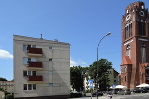 A modern building with balconies and a historic tower with a clock. - Apartment in Swinoujscie Near Baltic Beach (Swinoujscie)