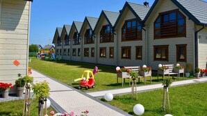 A row of modern, multi-story buildings with a consistent architectural style, featuring large windows and a sloped roof. - Holiday Homes Close to the Beach, Pool, Sauna (Kołobrzeg)