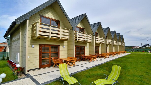 A row of chalet-style buildings with wooden balconies and outdoor seating areas. - Holiday Homes Close to the Beach, Pool, Sauna (Kołobrzeg)