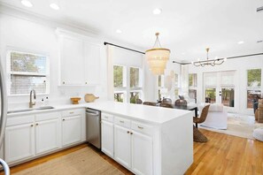 A modern kitchen with white cabinetry, a large island, and a dining area with wicker furniture.