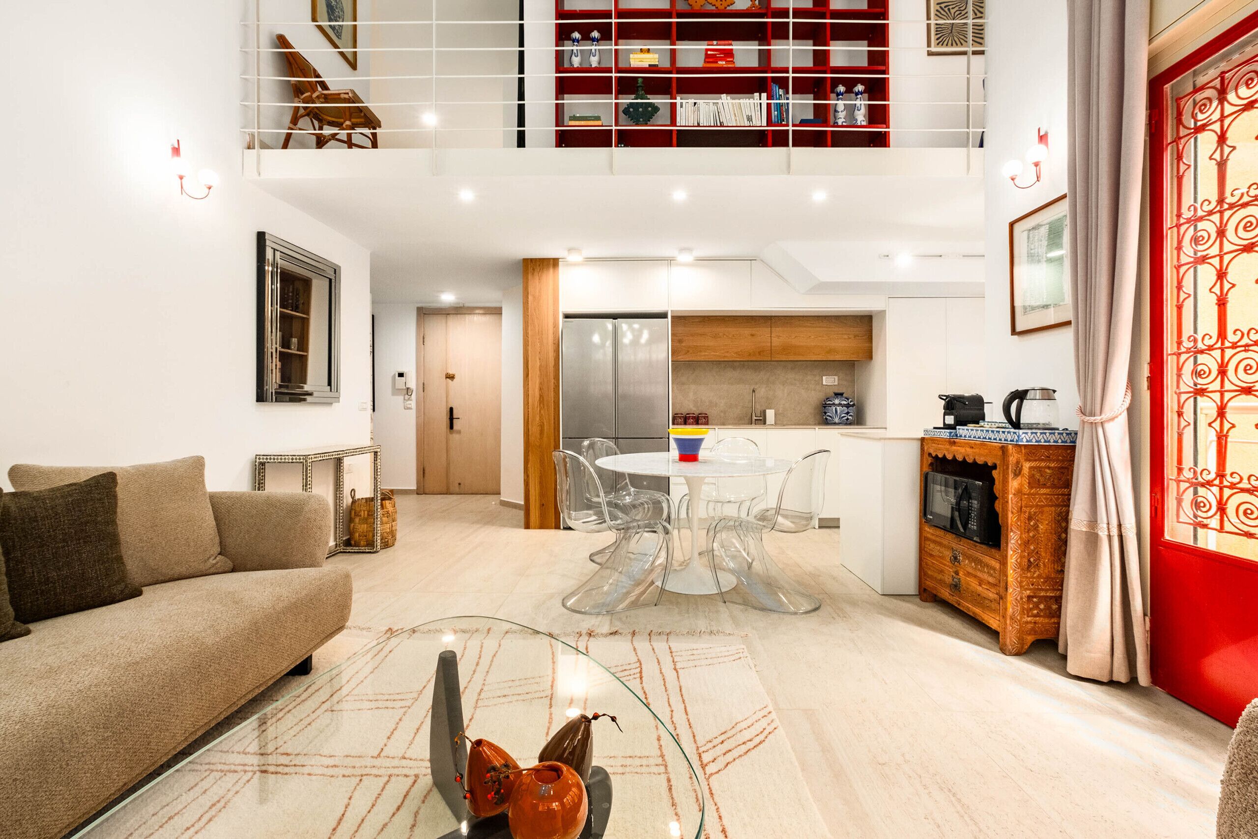 Un salon moderne avec un canapé, une table basse en verre et un coin repas comprenant une table et des chaises blanches.