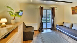 Ein modernes Wohnzimmer mit Sofa, Couchtisch, einer Pflanze und Blick ins Freie durch ein Fenster.