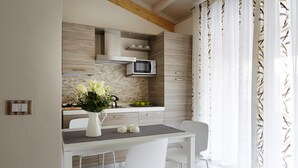 A modern kitchen with a microwave, a vase with flowers, and a dining area with chairs. - Bungalow in Caorle With Garden Furniture (Caorle)