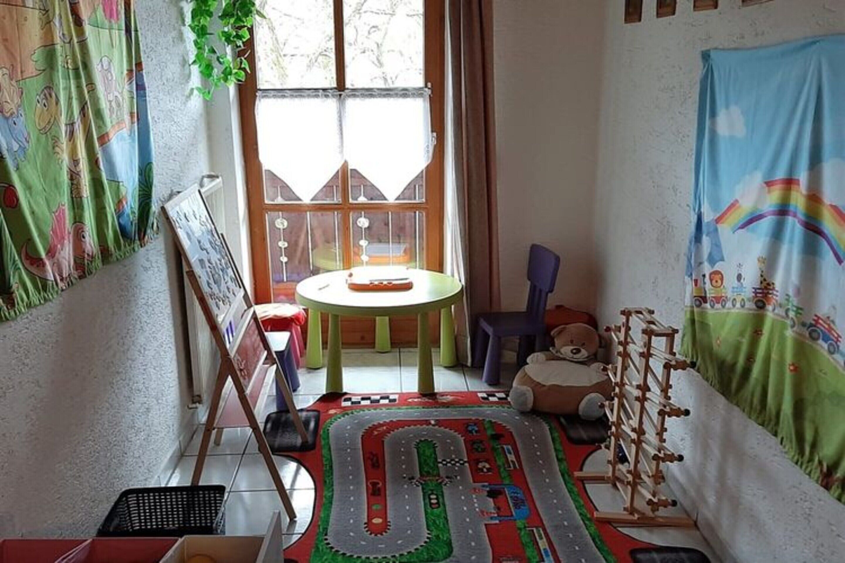 Ένα παιδικό δωμάτιο με ένα χαλάκι για παιχνίδι, παιχνίδια και ένα μικρό τραπέζι.
