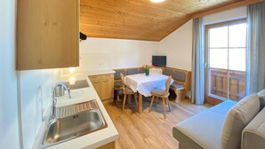 A compact kitchen with a sink, a dining area with a table and chairs, and a sofa in a living area. - Apartment in Filzmoos Near Ski Amade (Filzmoos)