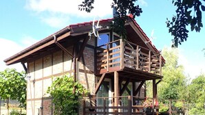 A rustic cabin with a wooden deck and a balcony, surrounded by greenery. - Holiday Home in Kolczewo With Lake Access (gmina Wolin)