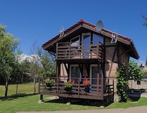 Eine zweistöckige Holzhütte mit Balkon, Satellitenschüssel und Blumentöpfen.