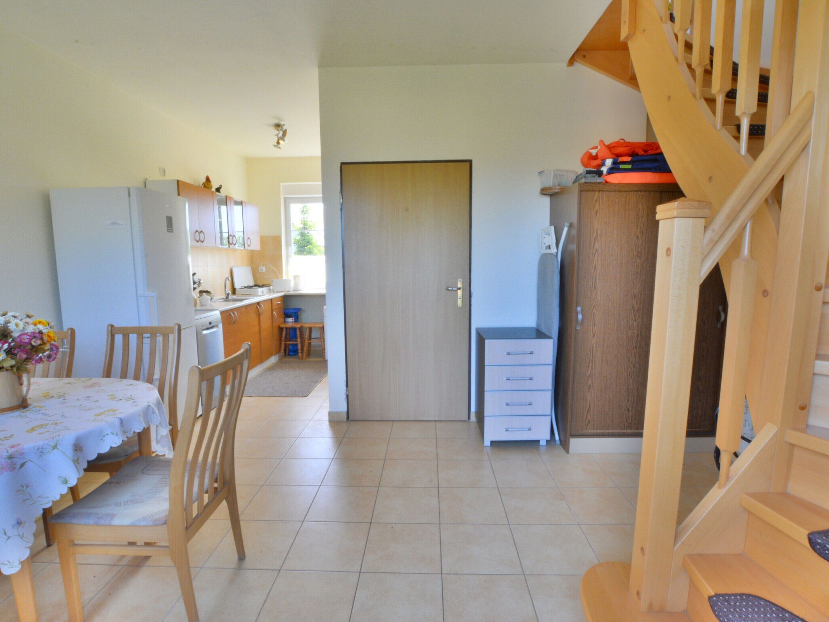 A kitchen with wooden cabinets, a dining table with chairs, and a staircase.