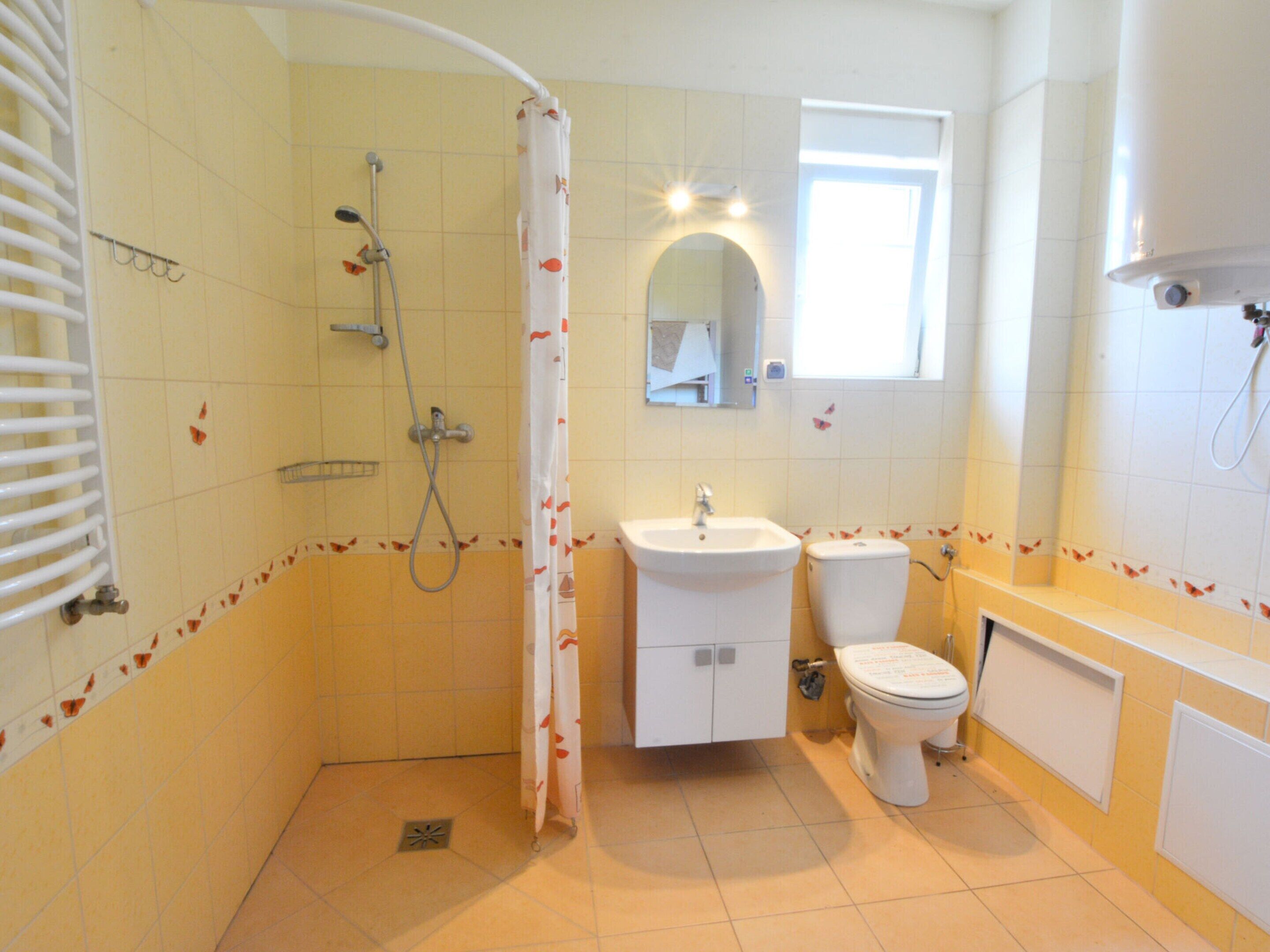 A bathroom with a shower, sink, toilet, and a mirror.