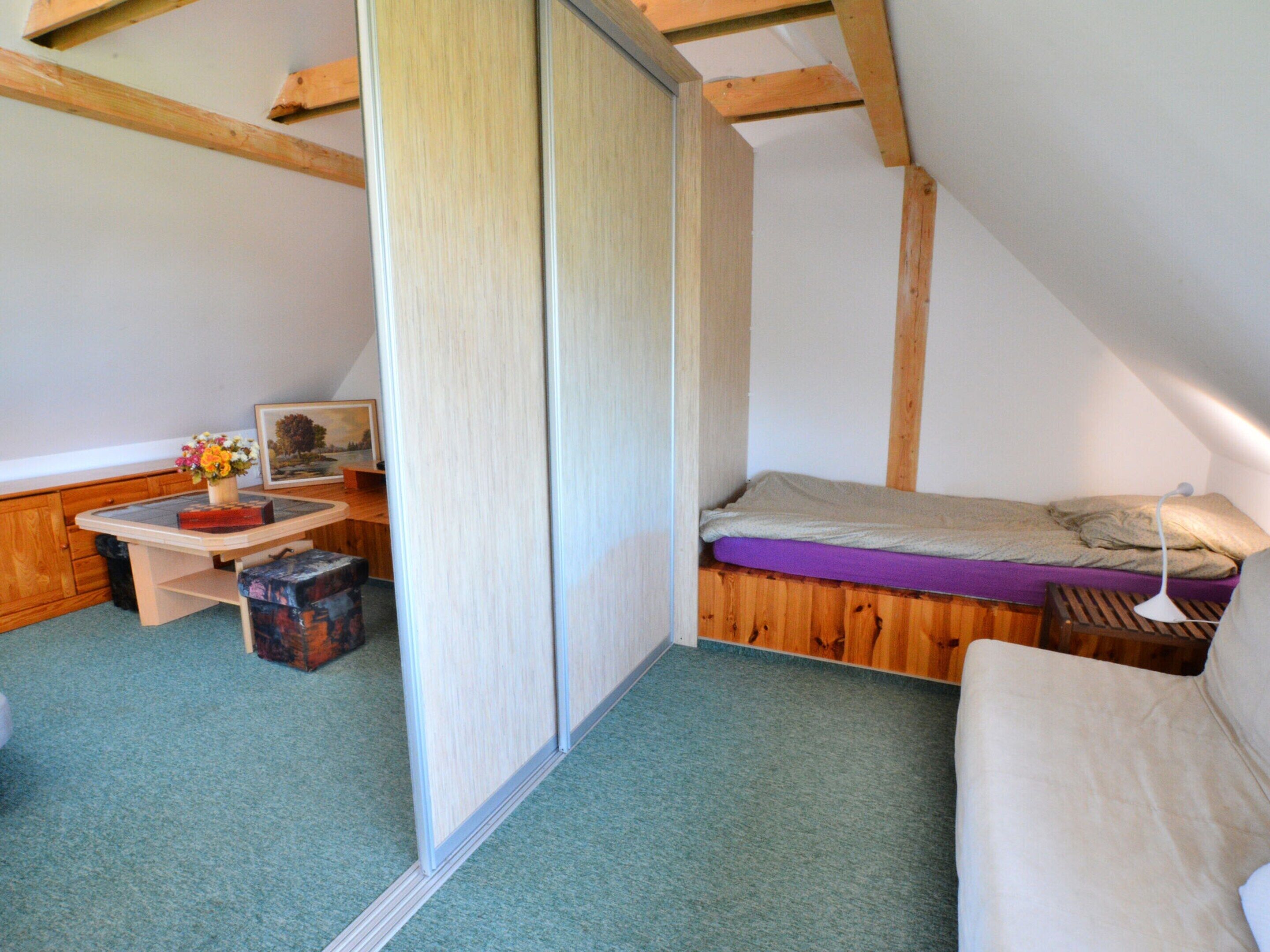 Une petite chambre mansardée, chaleureuse et accueillante, avec un lit superposé, un bureau avec une chaise et une fenêtre.