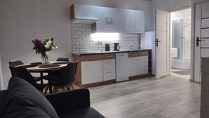 Une cuisine moderne avec des meubles blancs, un coin repas comprenant une table et des chaises, et une douche visible.