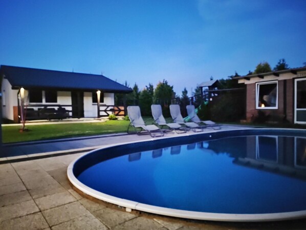 Relax by the calm pool surrounded by lounge chairs and a low fence.