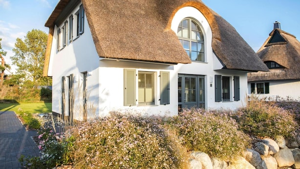 A white house with a thatched roof and a circular window.