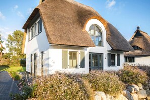 A white house with a thatched roof and a circular window. - Luxushaus Bodstedt mit Lagunenschwimmen (Fuhlendorf)