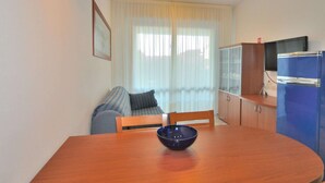 A compact living space with a dining table, a blue bowl, a sofa, a television, and a cabinet. - Apartment in Bibione Near the Beach (San Michele al Tagliamento)