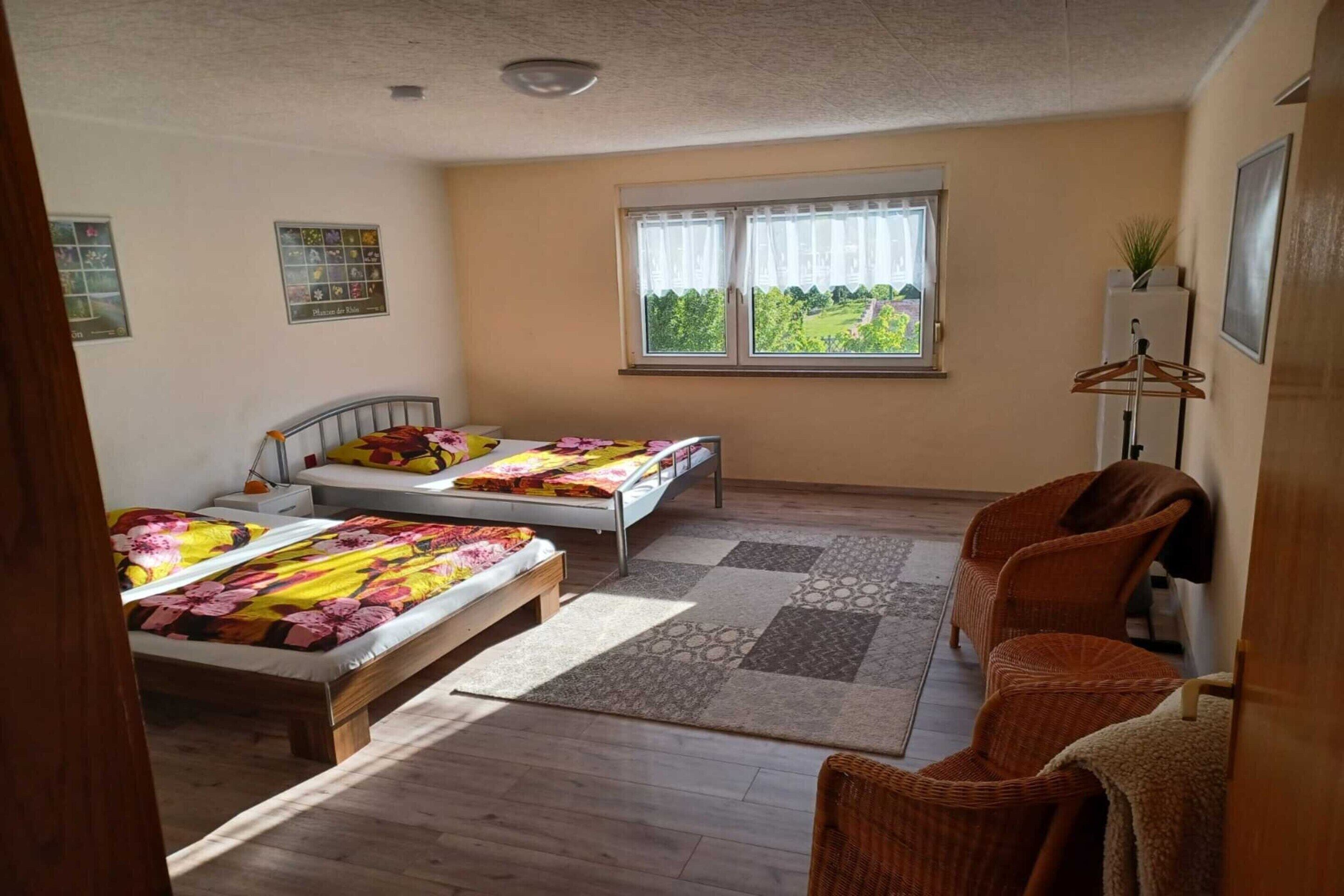 Une chambre avec deux lits, une fenêtre donnant sur un beau paysage, une chaise et une table de chevet.