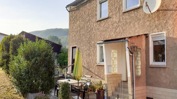 A two-story house with a patio area, a satellite dish, and a small garden. - Reihenhaus in Rhon Nahe Wasserkuppe (Kaltennordheim)