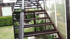 Eine Metalltreppe mit mehreren Stufen, die zu einem Hauseingang führt.