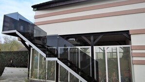 Ein modernes Gebäude mit einer gläsernen Treppe, die zu einem überdachten Bereich führt.