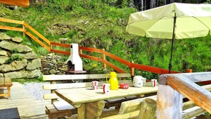En træterrasse med picnicborde, en stenvæg og en trappe i træ.
