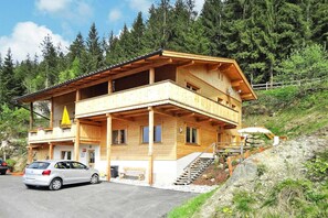 A two-story wooden cabin with a balcony, a car parked in front, and a staircase leading to the upper level. - Chalet in Zell am Ziller Near Ski Lifts (Rohrberg)