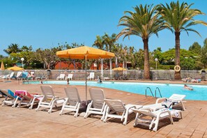 A pool area with sun loungers and umbrellas, surrounded by palm trees and a clear sky. - Bungalow, Maspalomas (San Bartolomé de Tirajana)