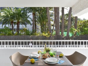 A dining table set outdoors with a view of palm trees and a white fence. - Pretty Apartment in Maspalomas Near the Beach-formerly TUI Ferienhaus (San Bartolomé de Tirajana)