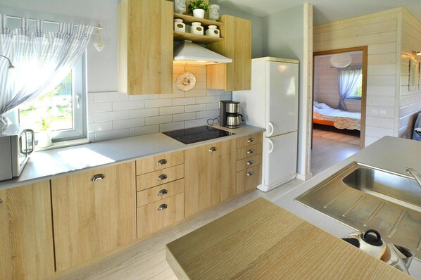 A compact kitchen with wooden cabinets, a built-in stove, and a refrigerator. - Comfortable Holiday Home With a Private Garden (Chociwel)
