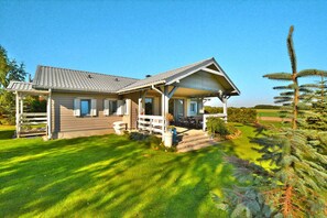 A two-story house with a covered porch, a fenced yard, and a well-maintained lawn. - Comfortable Holiday Home With a Private Garden (Chociwel)