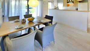 Un coin repas avec une table en bois, des chaises en osier et un panier de fruits.