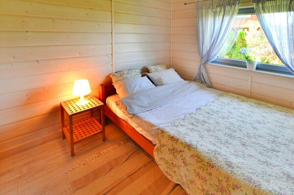 Une chambre confortable avec un lit en bois, une table de chevet avec une lampe et une fenêtre avec des rideaux.