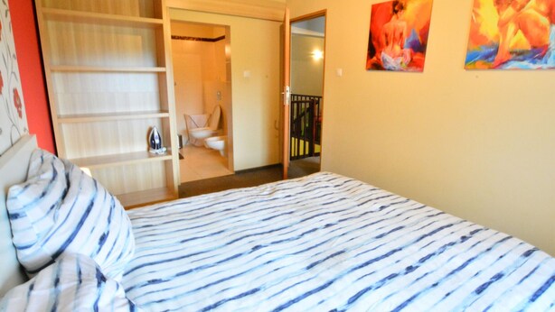 Een slaapkamer met een bed, een kledingkast en een badkamer die door een open deur zichtbaar is.