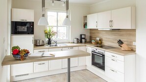 Una cocina moderna con armarios blancos, horno empotrado, microondas y encimera de madera.