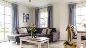 Una sala de estar moderna con un sofá modular, una mesa de centro y un comedor.