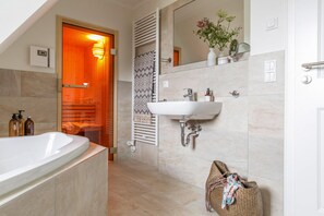 Une salle de bain moderne avec une baignoire sur pieds, un lavabo fixé au mur et un porte-serviettes.
