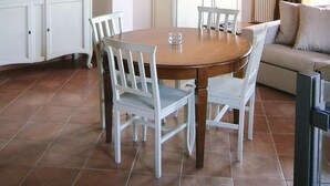 A dining area with a wooden table and chairs, a white cabinet, and a sofa. - Apartment in Lazise With Communal Pool (Lazise)