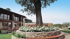 A building with a stone facade, large windows, and a patio area with a stone bench and outdoor seating. - Apartment in Lazise With Communal Pool (Lazise)