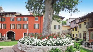 A courtyard with a stone bench, flower beds, and outdoor seating. - Apartment in Lazise With Communal Pool (Lazise)