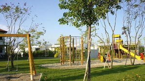 Un'area giochi con diverse strutture ricreative, circondata da erba e alberi.