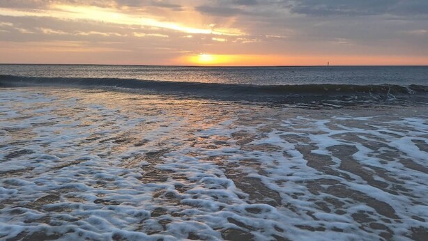 A beach with waves and a sunset in the background. - Ferienwohnung in Westerland (Sylt)