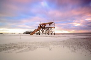 Una casa de playa con un muelle de madera y escaleras que conducen a una construcción pequeña.