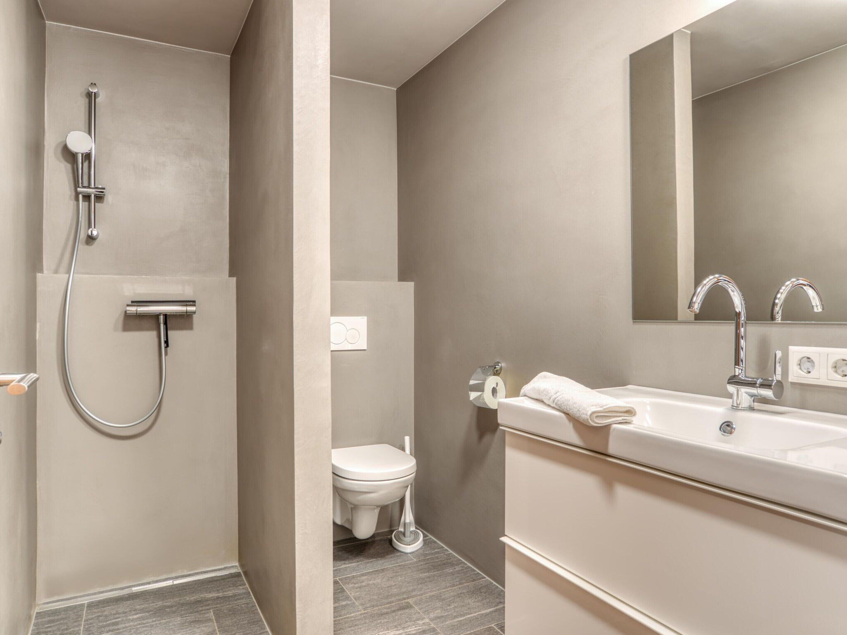 A modern bathroom with a shower, toilet, and sink.