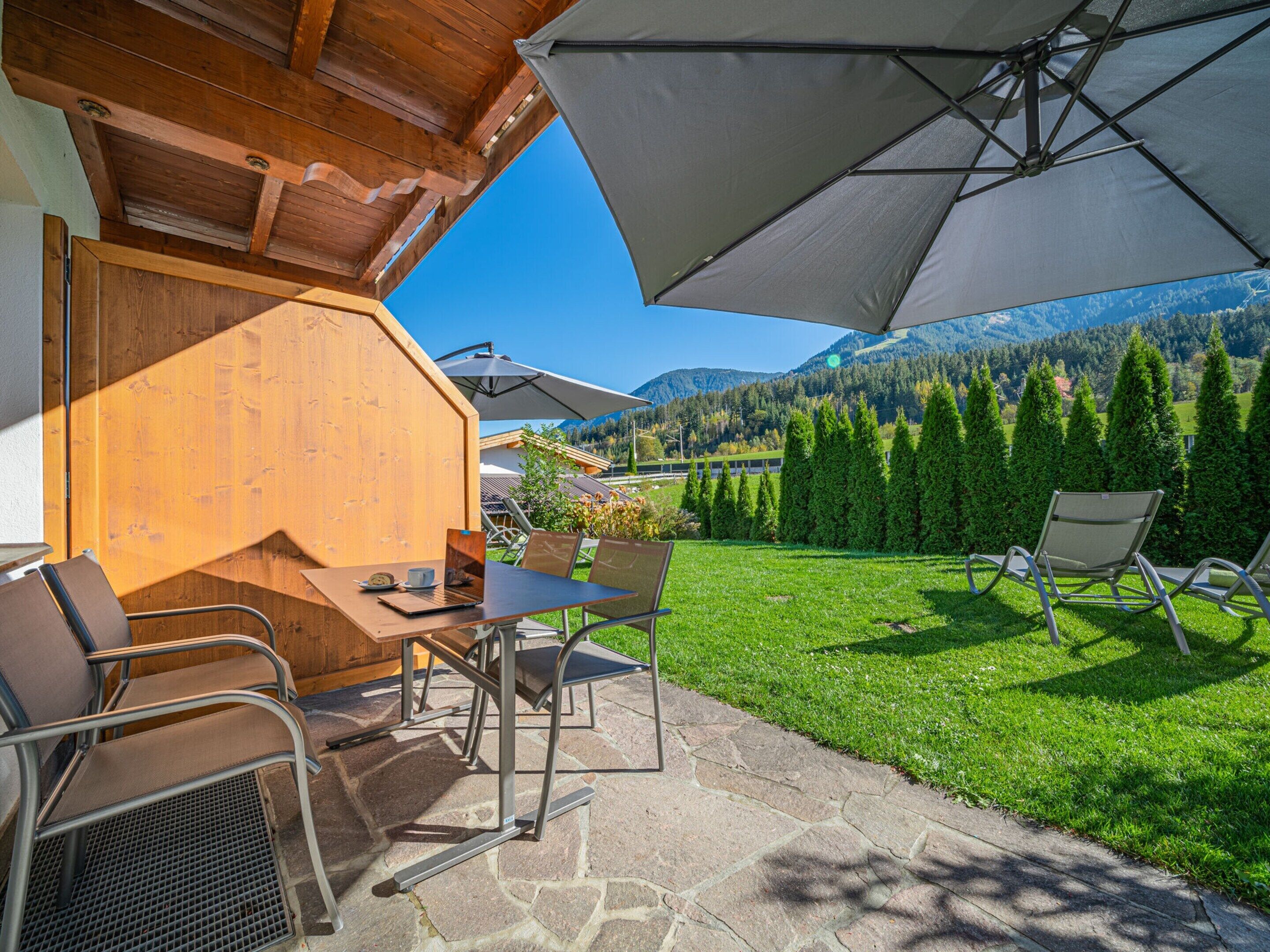 A patio area with stone flooring, outdoor seating, and a view of mountains and trees.
