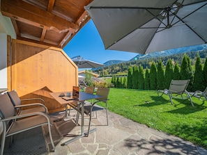 A patio area with stone flooring, outdoor seating, and a view of mountains and trees. - Apartment in Brixen Near Wilder Kaiser Gondola (Brixen im Thale)