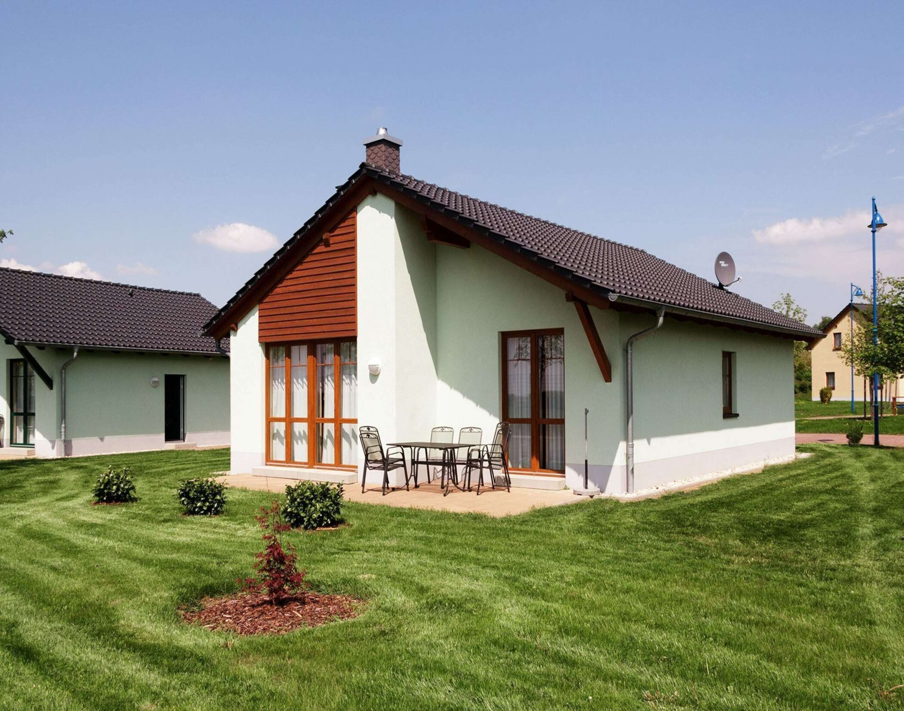 A two-story house with a sloped roof, a chimney, and a satellite dish.