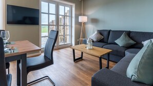 Ein modernes Wohnzimmer mit einem Holzesstisch, einer Couch und einem an der Wand befestigten Fernseher.