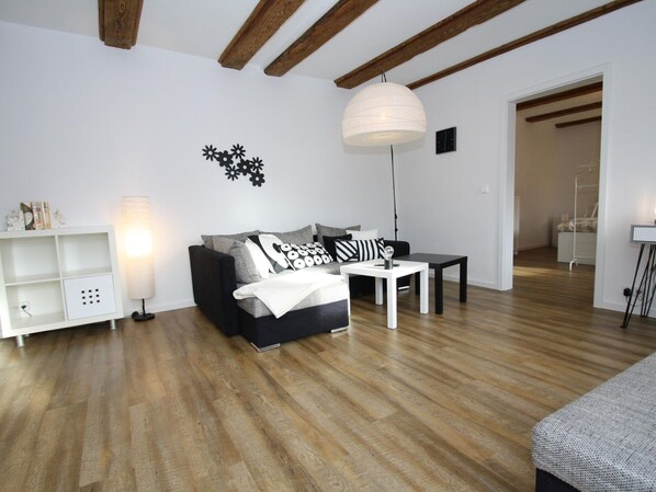 A modern living room with a sofa, a coffee table, and a lamp. There is a white shelf unit and a clock on the wall. - Ferienhaus mit 2 Kaminofen in Zarchlin (Barkhagen)