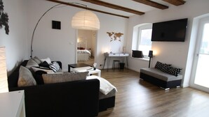 Un salon moderne avec un canapé, une table à manger et un téléviseur fixé au mur.